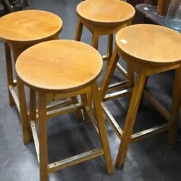 Set of four handcrafted solid wood stools with a rustic finish, perfect for farmhouse or vintage-style decor.